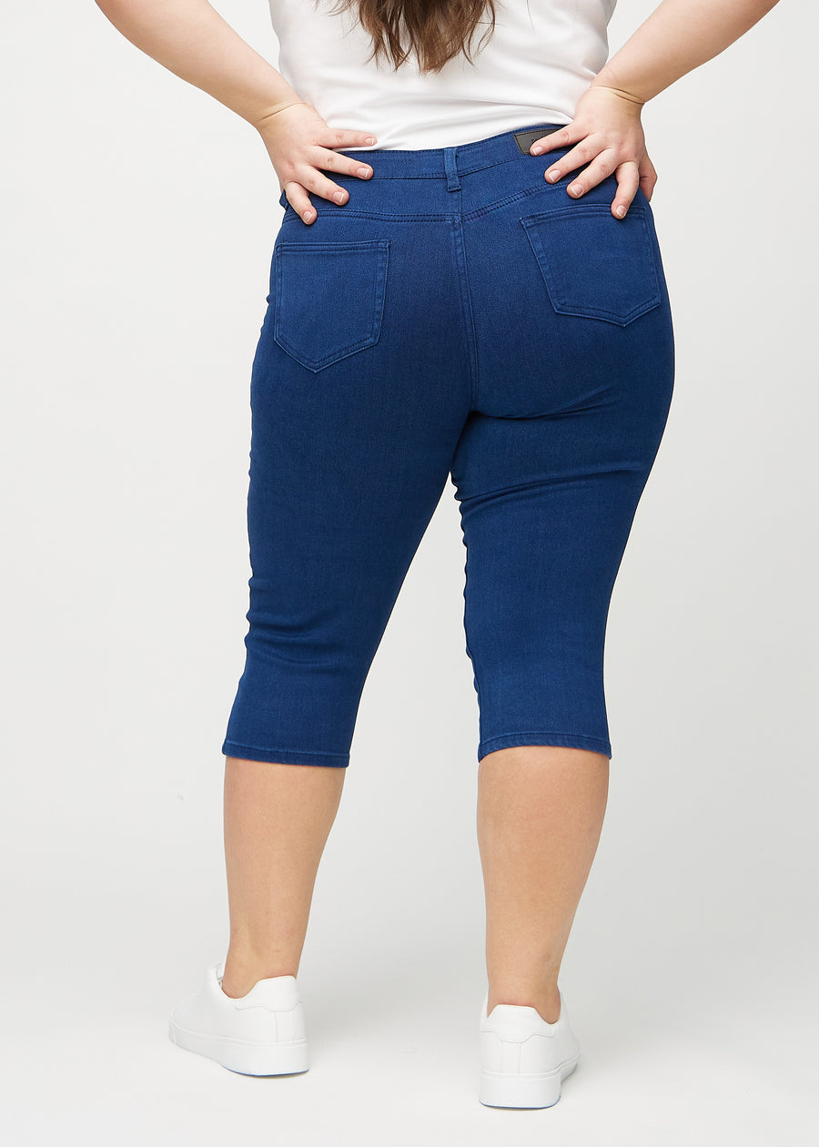 Skinnycapris för kvinnor i mörkblått jeanstyg, färgen Royals. Bakifrån på en plus size-modell, med fokus på passform och bakfickor.