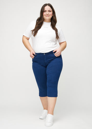Skinnycapris för kvinnor i mörkblått jeanstyg, färgen Royals. Helbild av en plus size-modell som bär capris.