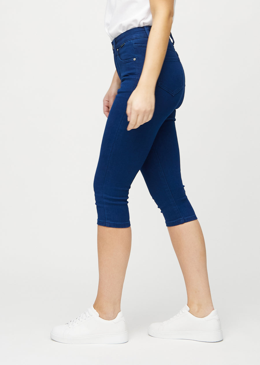 Skinnycapris för kvinnor i mörkblått jeanstyg, färgen Royals. Från sidan på en modell, med åtsittande passform.