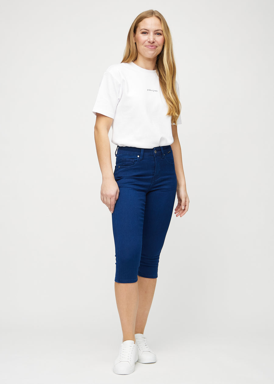 Skinnycapris för kvinnor i mörkblått jeanstyg, färgen Royals. Helbild av en modell som bär capris.