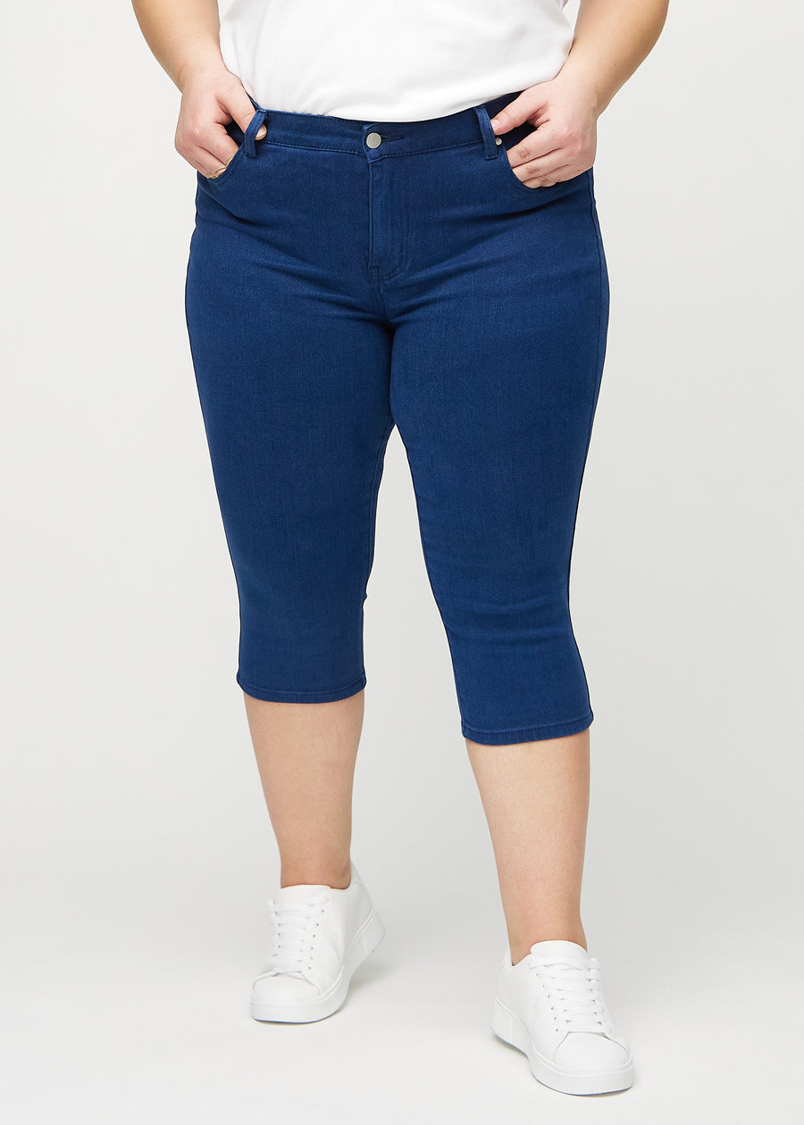 Skinnycapris för kvinnor i mörkblått jeanstyg, färgen Royals. Framifrån på en plus size-modell, med åtsittande ben till strax under knät.