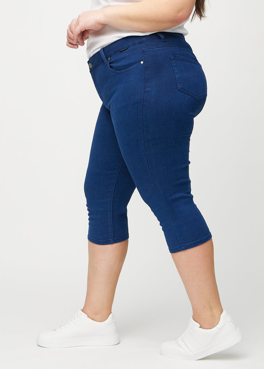 Skinnycapris för kvinnor i mörkblått jeanstyg, färgen Royals. Från sidan på en plus size-modell, med åtsittande passform.