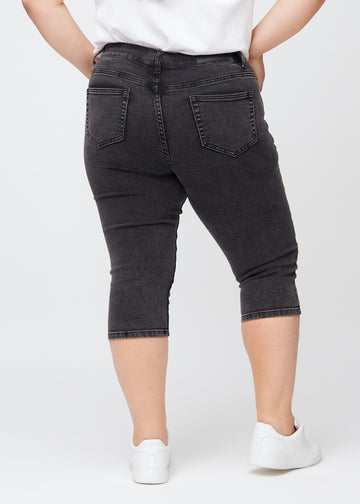 Skinnycapris för kvinnor i mörkgrå denim, färgen Shadows. Bakifrån på en plus size-modell, med fokus på passform och bakfickor.