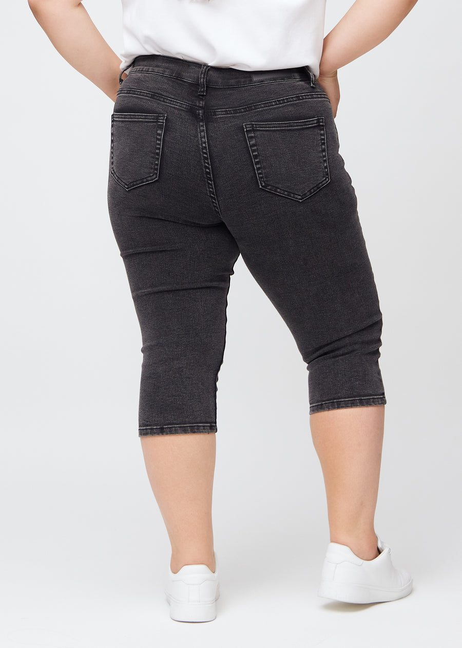 Skinnycapris för kvinnor i mörkgrå denim, färgen Shadows. Bakifrån på en plus size-modell, med fokus på passform och bakfickor.