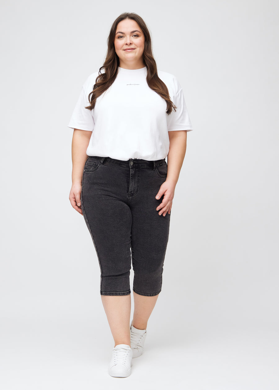 Skinnycapris för kvinnor i mörkgrå denim, färgen Shadows. Helbild av en plus size-modell som bär capris.