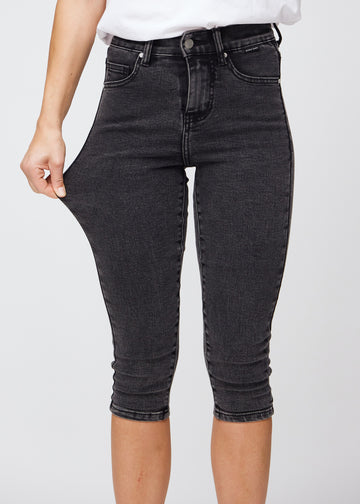 Skinnycapris för kvinnor i mörkgrå denim, färgen Shadows. En modell drar i tyget för att visa flexibiliteten.