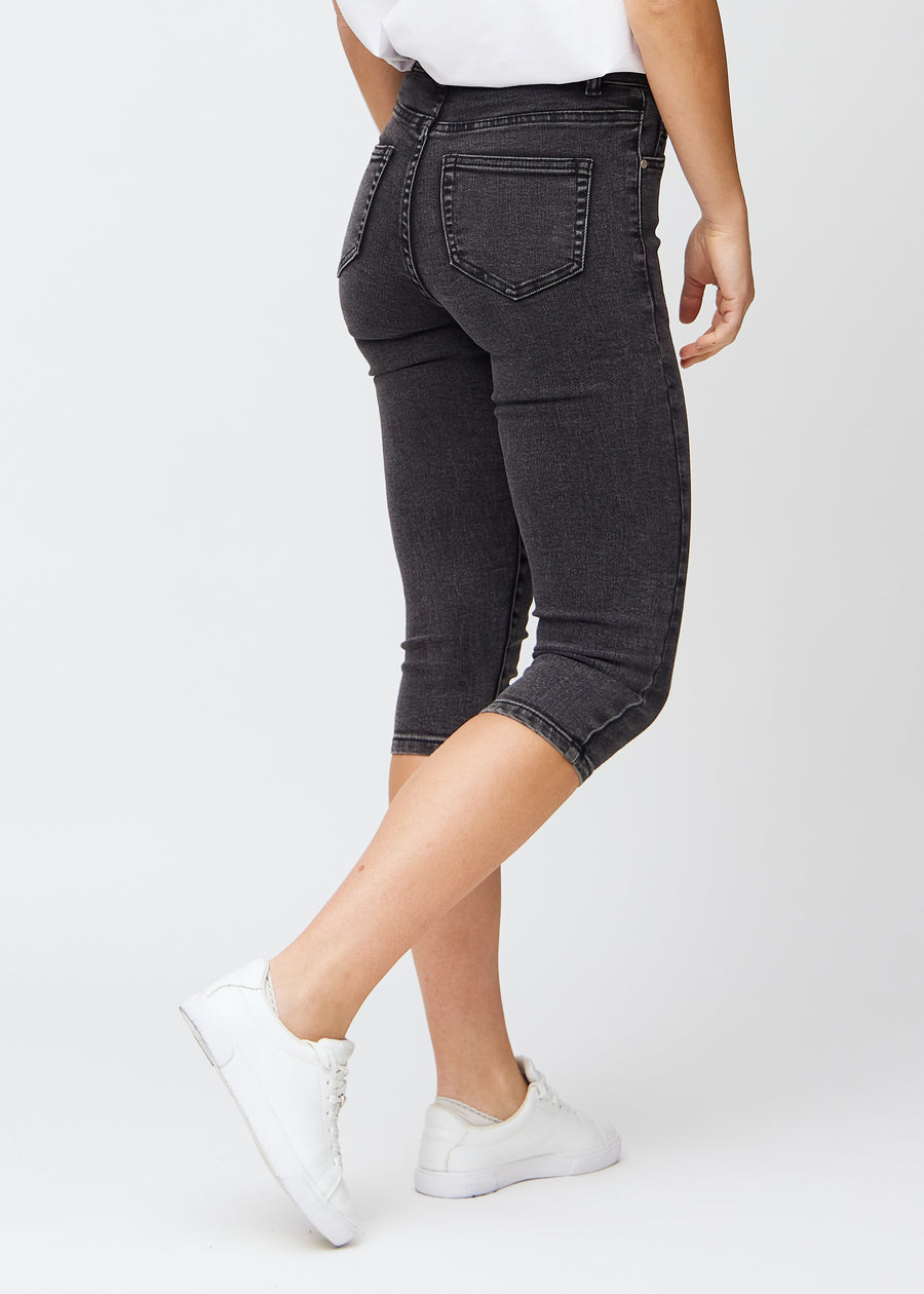 Skinnycapris för kvinnor i mörkgrå denim, färgen Shadows. Bakifrån på en modell, med fokus på passform och bakfickor.