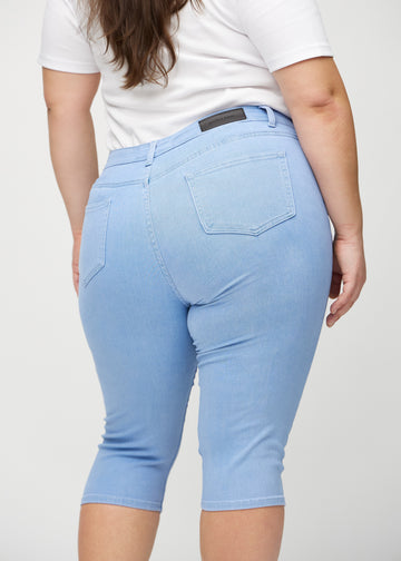 Ljusblå skinny capris sett bakifrån på nära håll på en plus-size-modell för att visa detaljer.