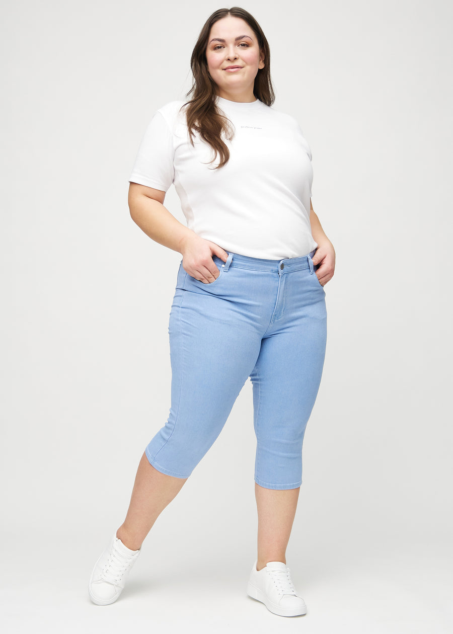 Helbild av en plus-size-modell i ljusblå skinny capris.