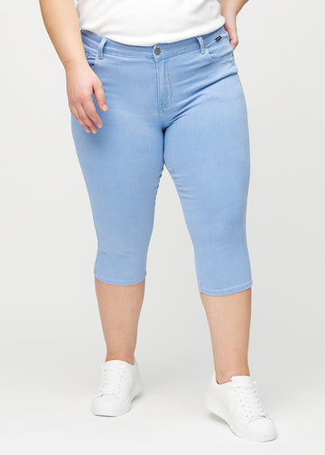 Ljusblå skinny capris, modellnamn Skies, som sitter tätt mot benet och slutar precis under knät på en plus-size-modell, sett framifrån.