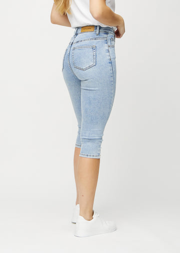 Skinnycapris för kvinnor i ljusblå denim, färgen Waves. Bakifrån på en modell, med fokus på passform och bakfickor.