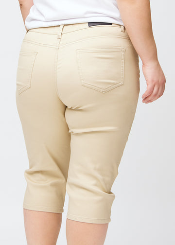 Slimcapris för kvinnor i beige jeanstyg, färgen Gazelles. Närbild bakifrån på en plus size-modell, med fokus på bakfickor och sömmar.