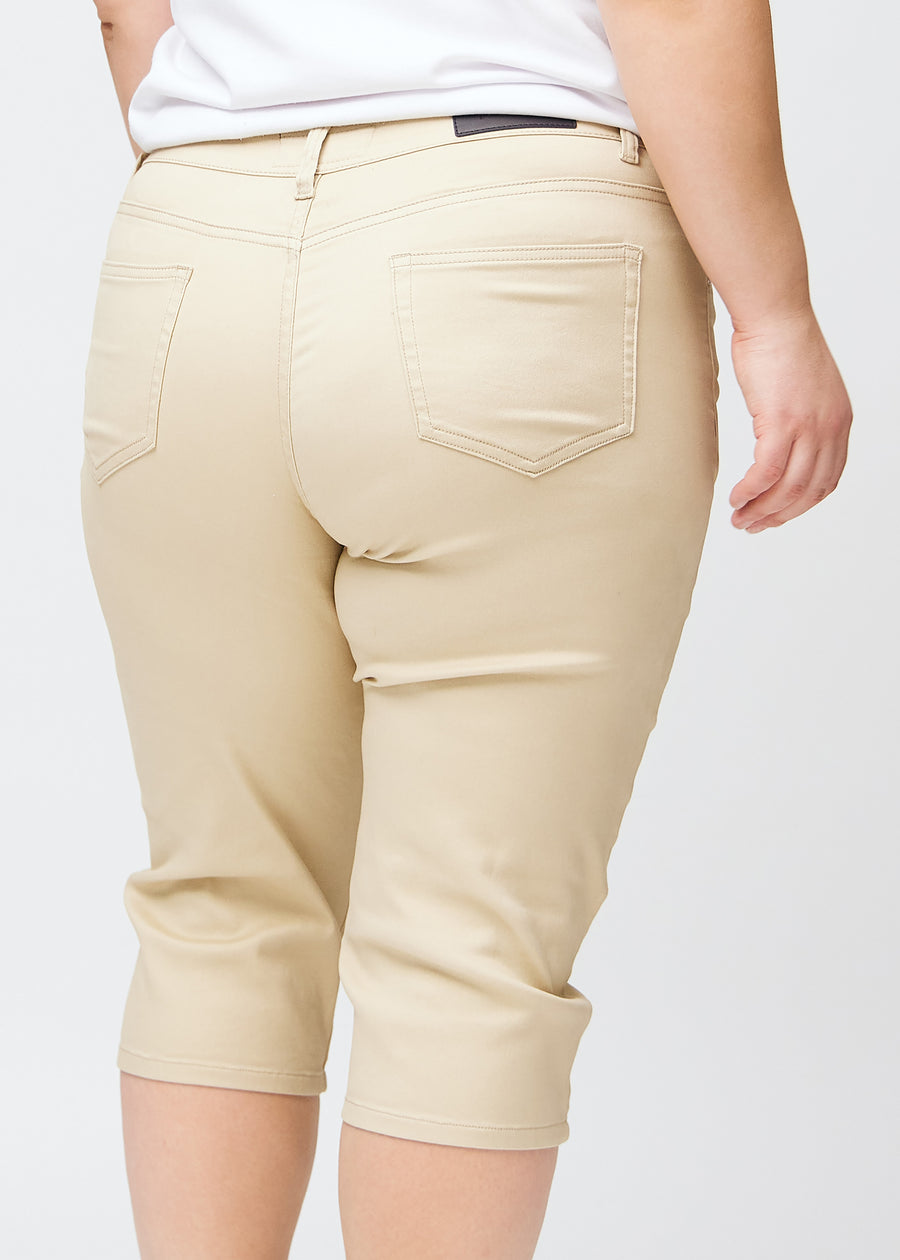 Slimcapris för kvinnor i beige jeanstyg, färgen Gazelles. Närbild bakifrån på en plus size-modell, med fokus på bakfickor och sömmar.