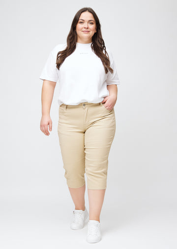 Slimcapris för kvinnor i beige jeanstyg, färgen Gazelles. Helbild av en plus size-modell som bär slimcapris.