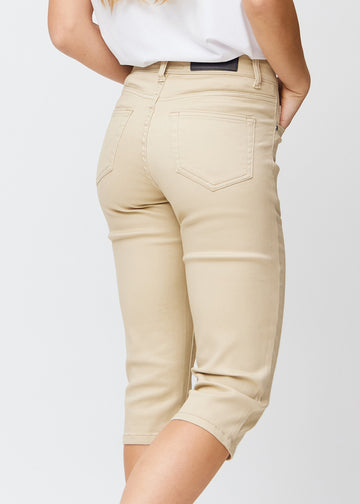 Slimcapris för kvinnor i beige jeanstyg, färgen Gazelles. Närbild bakifrån på en modell, med fokus på bakfickor och sömmar.