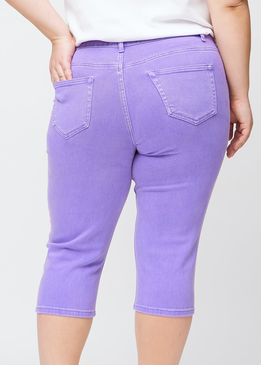 Slimcapris för kvinnor i pastellila jeanstyg, färgen Lavenders. Närbild bakifrån på en plus size-modell, med fokus på bakfickor och sömmar.