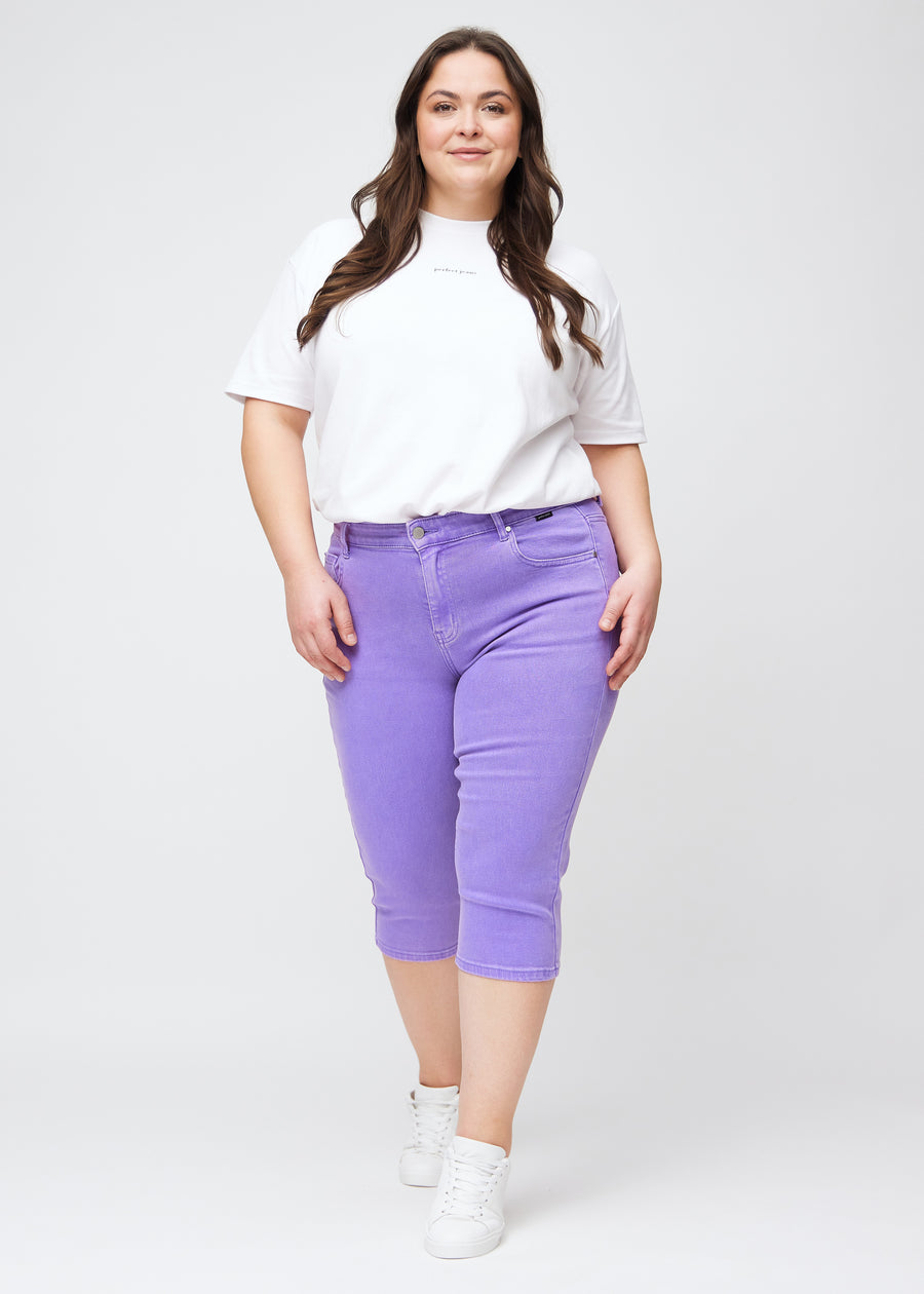 Slimcapris för kvinnor i pastellila jeanstyg, färgen Lavenders. Helbild av en plus size-modell som bär slimcapris.