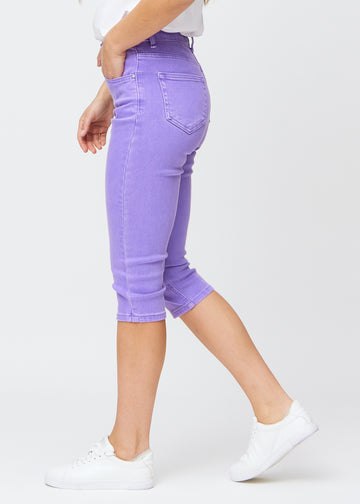 Slimcapris för kvinnor i pastellila jeanstyg, färgen Lavenders. Från sidan på en modell, med figursydd passform och medelhög midja (Mid Rise).