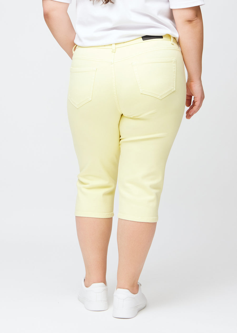 Slimcapris för kvinnor i pastellljusgult jeanstyg, färgen Lemonades. Bakifrån på en plus size-modell, med fokus på passform, längd och bakfickor.