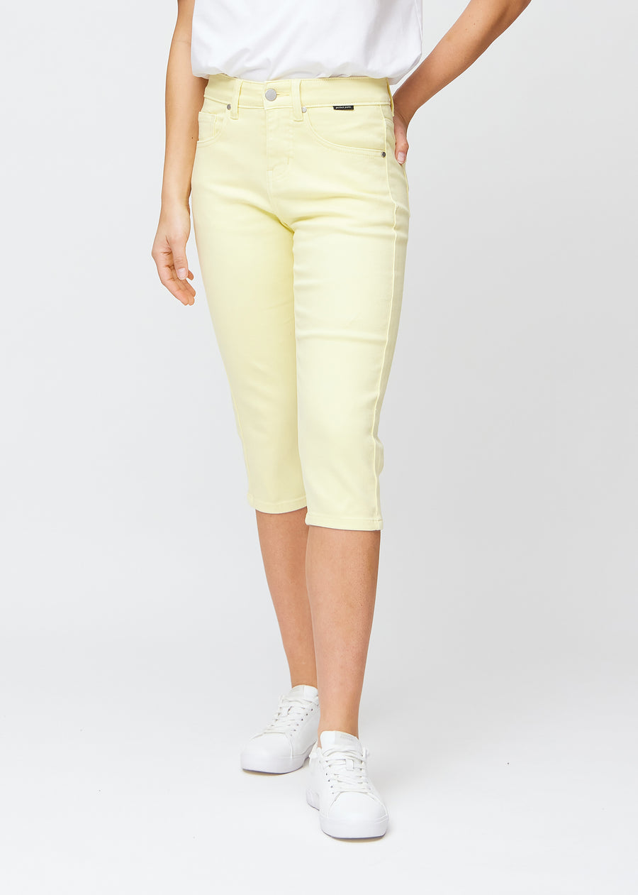 Slimcapris för kvinnor i pastellljusgult jeanstyg, färgen Lemonades. Framifrån på en modell, med figursydd passform till strax under knät.