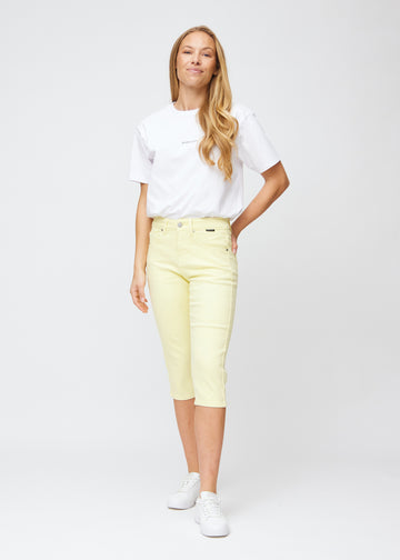 Slimcapris för kvinnor i pastellljusgult jeanstyg, färgen Lemonades. Helbild av en modell som bär slimcapris.