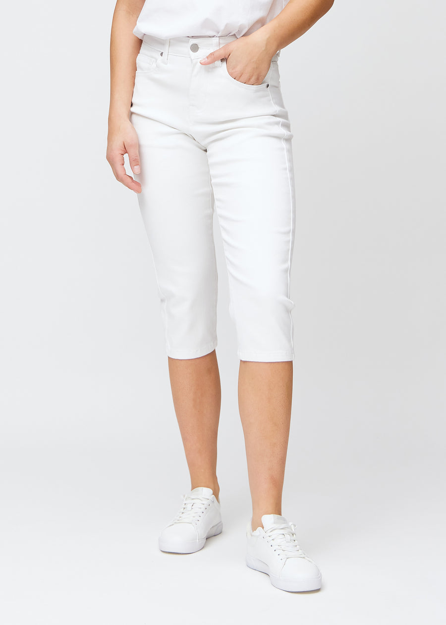 Slimcapris för kvinnor i vitt jeanstyg, färgen Marguerites. Framifrån på en modell, med figursydd passform till strax under knät.