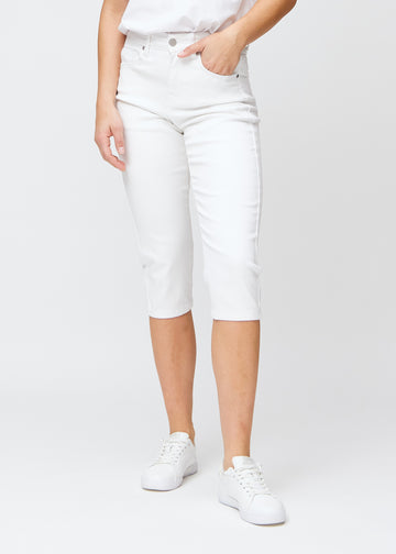 Slimcapris för kvinnor i vitt jeanstyg, färgen Marguerites. Framifrån på en modell, med figursydd passform till strax under knät.