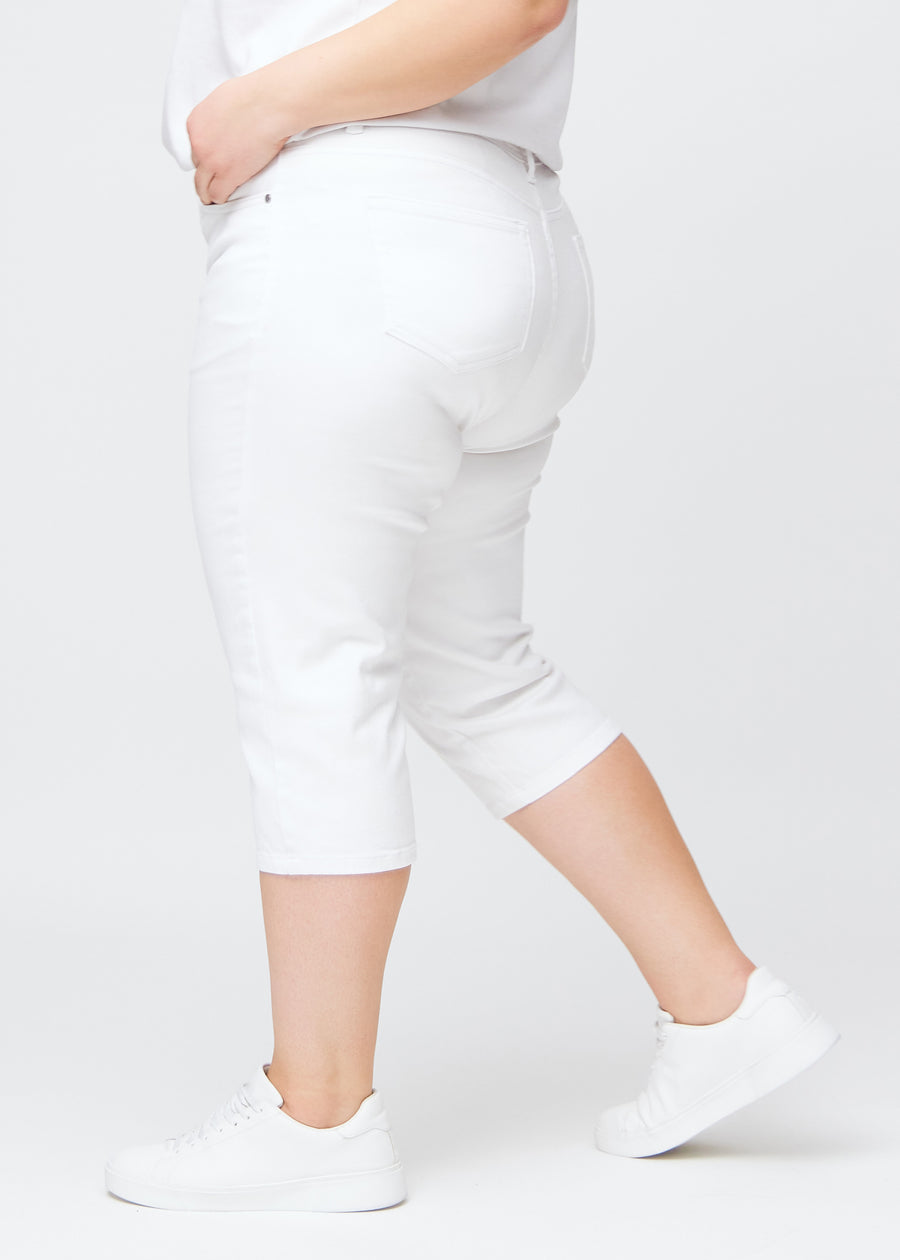 Slimcapris för kvinnor i vitt jeanstyg, färgen Marguerites. Från sidan på en plus size-modell, med figursydd passform och medelhög midja (Mid Rise).