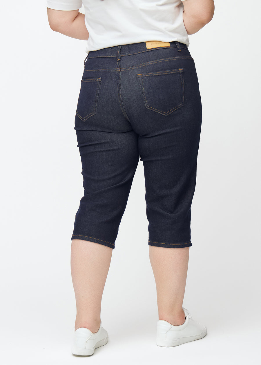 Mörkblå denim capris för dam i färgen Midnights sett bakifrån på plus-size modell.