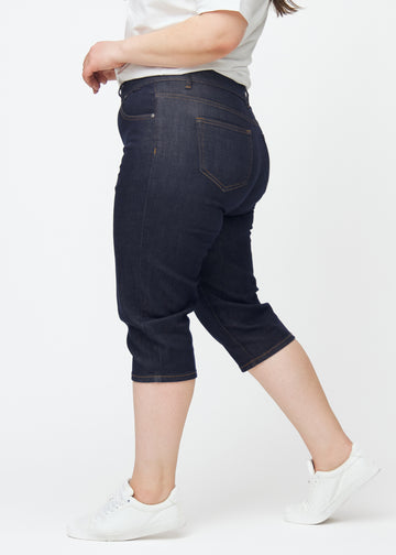 Mörkblå denim capris för dam i färgen Midnights med slim passform sett från sidan på plus-size modell.
