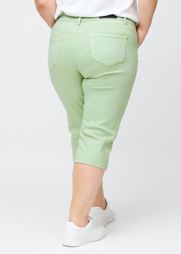 Slimcapris för kvinnor i pastellljusgrönt jeanstyg, färgen Mints. Bakifrån på en plus size-modell, med fokus på passform, längd och bakfickor.