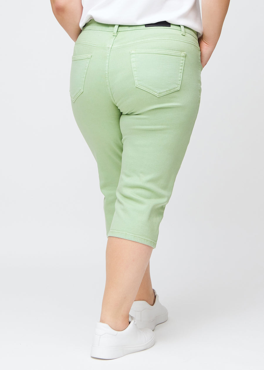 Slimcapris för kvinnor i pastellljusgrönt jeanstyg, färgen Mints. Bakifrån på en plus size-modell, med fokus på passform, längd och bakfickor.