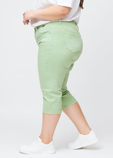 Slimcapris för kvinnor i pastellljusgrönt jeanstyg, färgen Mints. Från sidan på en plus size-modell, med figursydd passform och medelhög midja (Mid Rise).