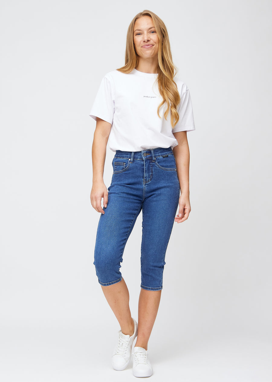 Slimcapris för kvinnor i mörkblå denim, färgen Oceans. Helbild av en modell som bär slimcapris.