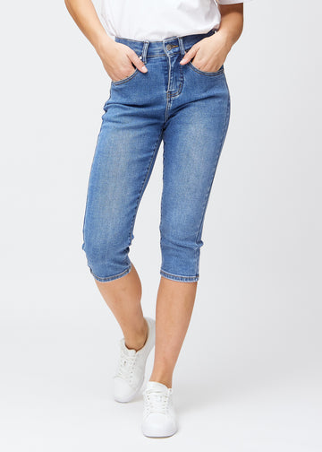 Slimcapris för kvinnor i blå denim, färgen Rivers. Framifrån på en modell, med figursydd passform till strax under knät.
