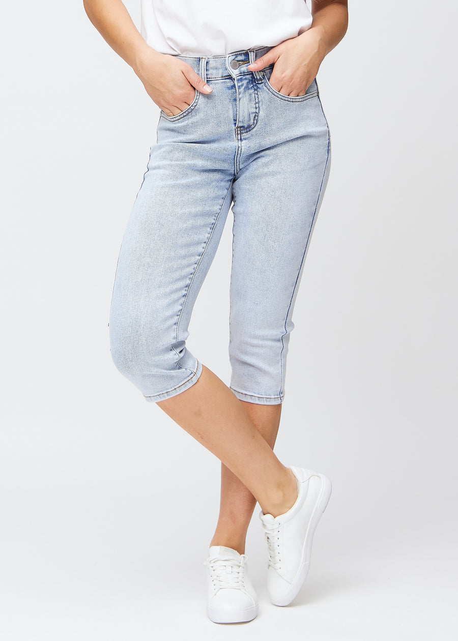 Slimcapris för kvinnor i ljusblå denim, färgen Waves. Framifrån på en modell, med figursydd passform till strax under knät.