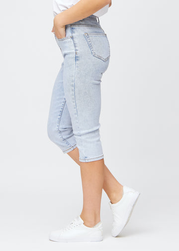 Slimcapris för kvinnor i ljusblå denim, färgen Waves. Från sidan på en modell, med figursydd passform och medelhög midja (Mid Rise).