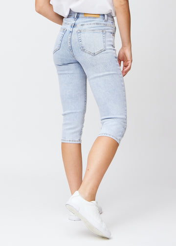 Slimcapris för kvinnor i ljusblå denim, färgen Waves. Bakifrån på en modell, med fokus på passform, längd och bakfickor.