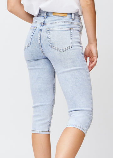 Slimcapris för kvinnor i ljusblå denim, färgen Waves. Närbild bakifrån på en modell, med fokus på bakfickor och sömmar.