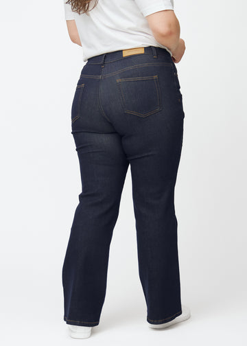 Djupt mörkblå denim jeans för kvinnor i färgen Midnights sedd bakifrån på plus size-modell.