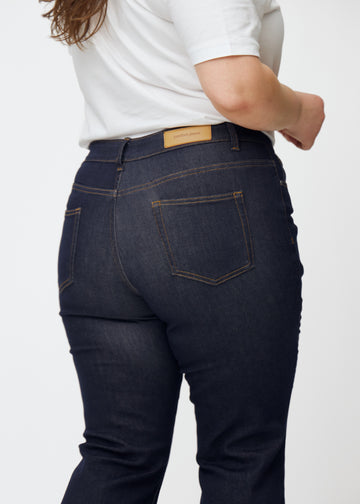 Djupt mörkblå denim jeans för kvinnor i färgen Midnights sedd bakifrån i närbild på plus size-modell.