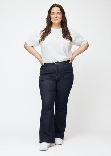 Helbild av plus size-modell i djupt mörkblå denim jeans för kvinnor i färgen Midnights med bootcut-passform.