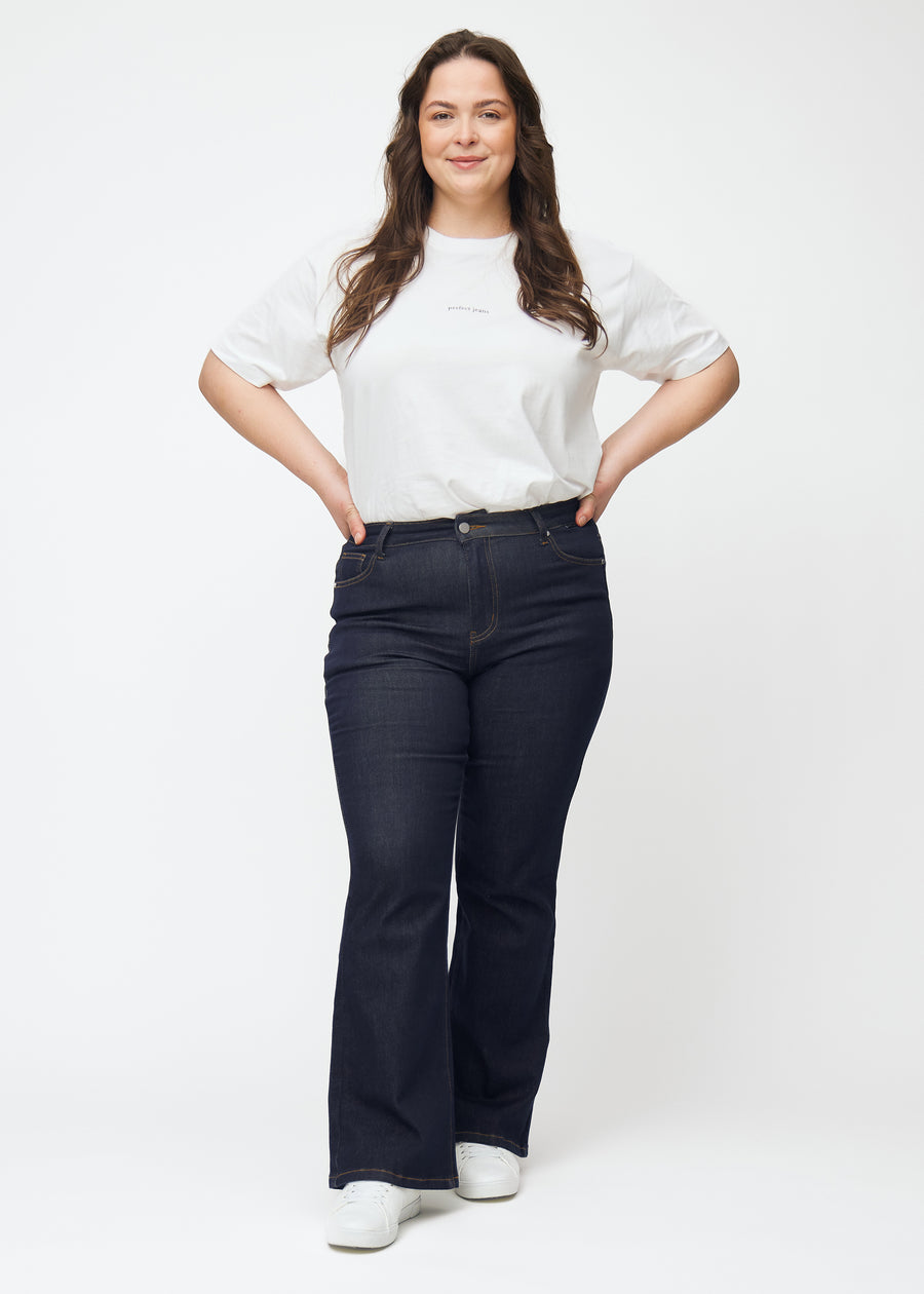 Helbild av plus size-modell i djupt mörkblå denim jeans för kvinnor i färgen Midnights med bootcut-passform.