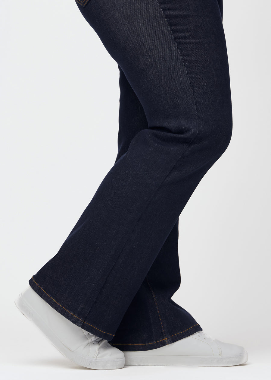 Djupt mörkblå denim jeans för kvinnor i färgen Midnights med bootcut-passform sedd i närbild vid anklarna på plus size-modell för att visa den lätta vidden.