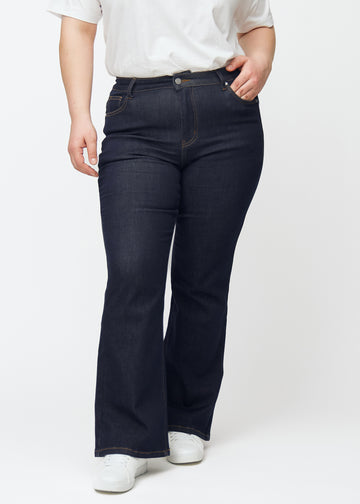 Djupt mörkblå denim jeans för kvinnor i färgen Midnights med bootcut-passform sedd framifrån på plus size-modell.