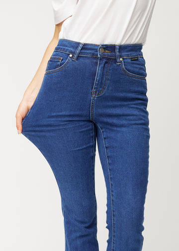 Mörkblå mid-rise bootcutjeans i färgen Oceans. En modell drar i jeanstyget vid låret för att visa stretchen.