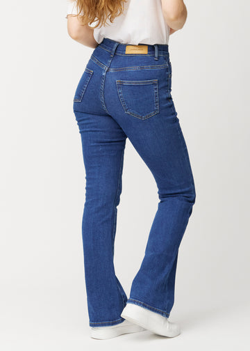 Mörkblå mid-rise bootcutjeans i färgen Oceans. Bakifrån på en modell, så att hela passformen syns.