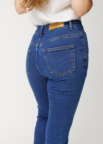 Mörkblå mid-rise bootcutjeans i färgen Oceans. Närbild bakifrån på en modell som visar detaljerna.
