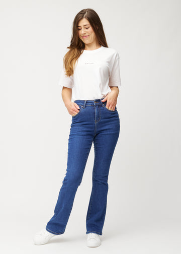 Mörkblå mid-rise bootcutjeans i färgen Oceans. Helbild av en modell i jeansen.
