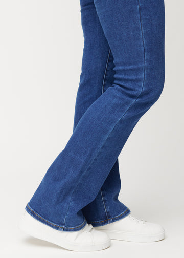 Mörkblå mid-rise bootcutjeans i färgen Oceans. Närbild vid ankeln på en modell som visar den lätta utsvängningen nedtill.